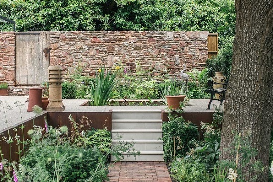 Garden path in Dorset Antique Clay Pavers leads to beige sandstone steps between beds.