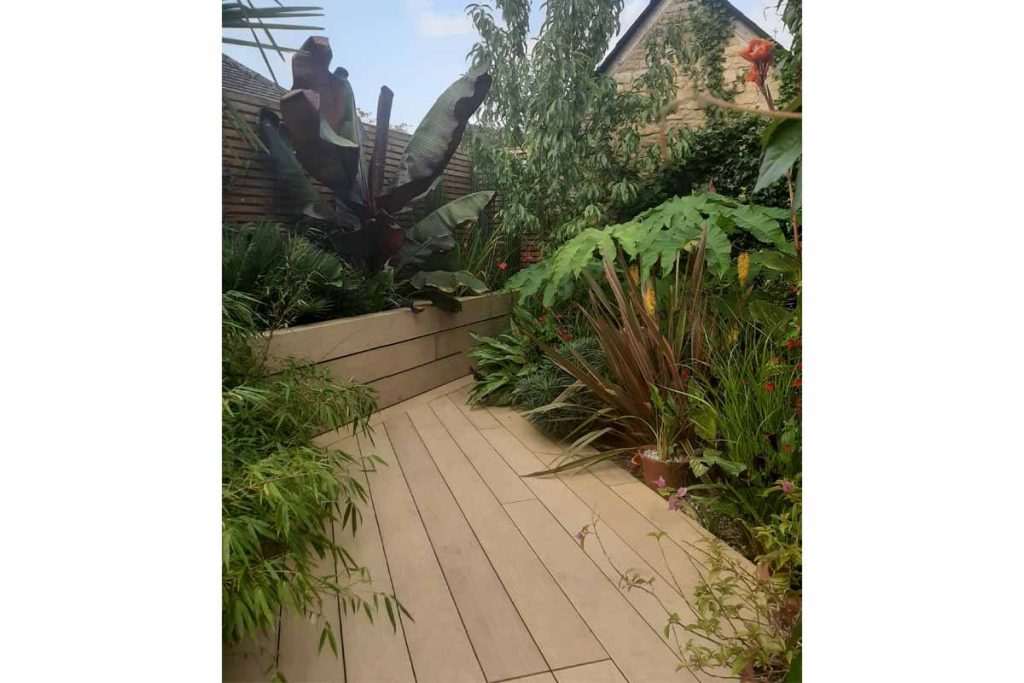 Small garden with amber designboard with raised bed and exotic planting 