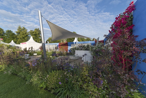 Sail canopy offers shelter over travertine and wood-effect porcelain paving. Esra Parr's World garden at RHS Hampton Court 2015.