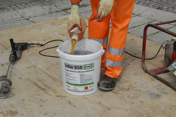 Person in orange day-glo trousers pouring hardener into GftK 850 jointing compound.