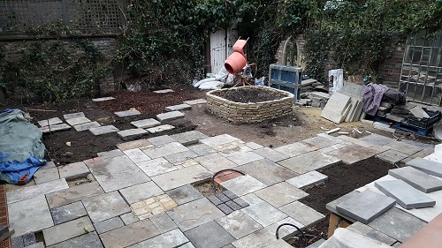 Reclaimed Yorkstone being laid around raised bed for an aged, secret garden feel. 