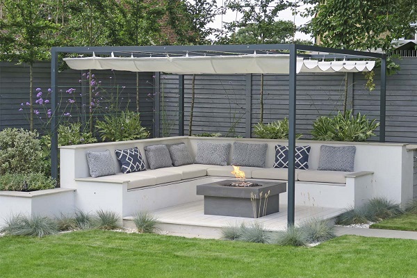 Built seating on 2 sides of raised composite decking with fire table and pergola