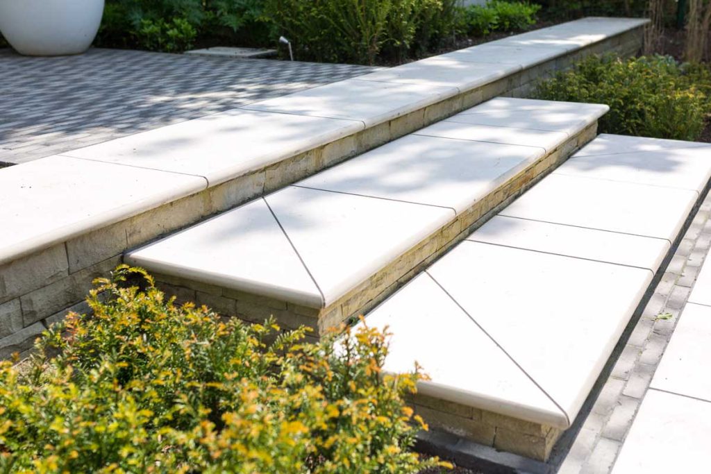 3 Florence White porcelain bullnose steps, with decoratively cut slabs with mitred corners between planted beds