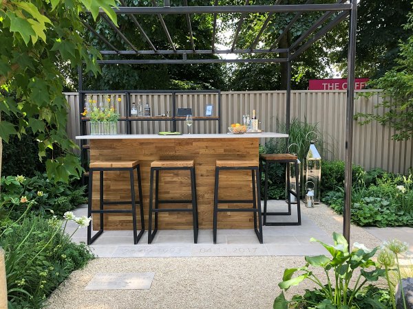 Outdoor bar with stools on Jura Beige paving next to fence.