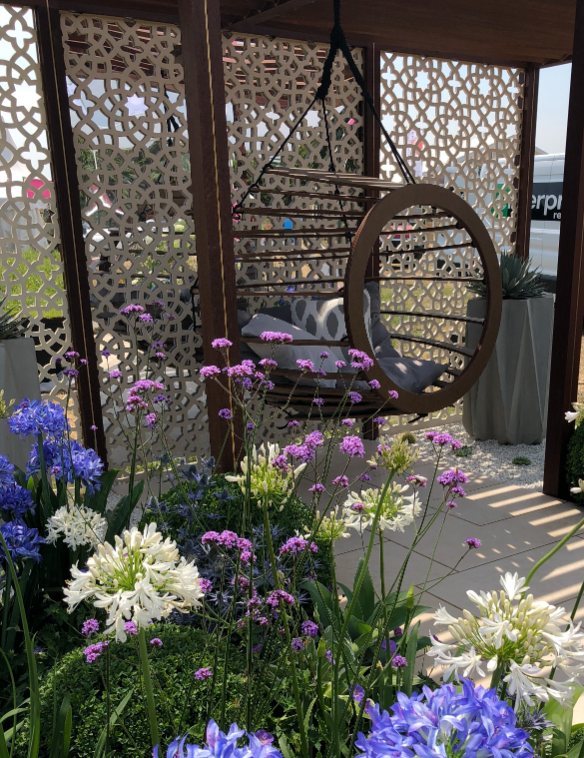 Blue hydrangeas, white alliums with hanging seat under decorative pergola