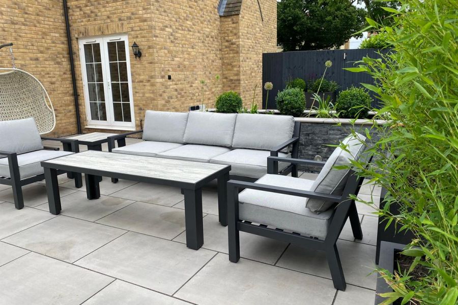 Modern lounge set on Polished Concrete 600x900 porcelain patio slabs, with house wall behind. 