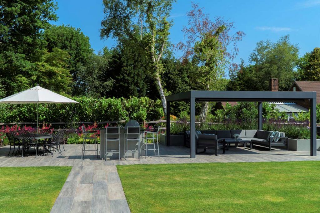 Cinder porcelain paving path leads across lawn to patio with pergola, by Karen McClure Garden Design