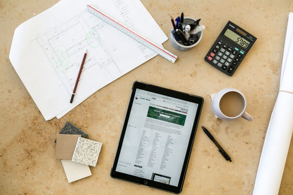 View straight down onto desktop with calculator, pens, tablet and spec sheet.