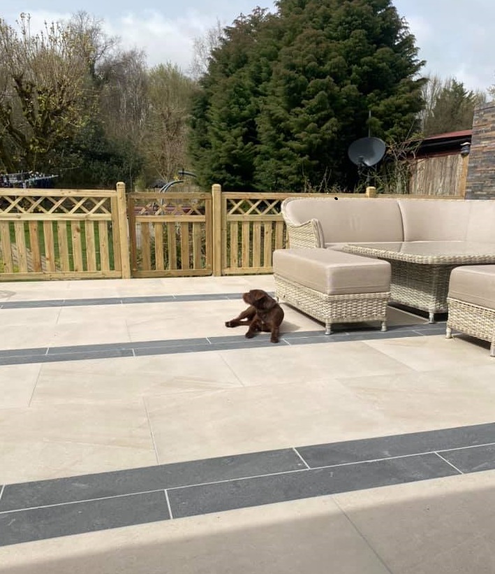 Dog sits on large patio of Ash Beige slabs and Platinum Grey porcelain planks