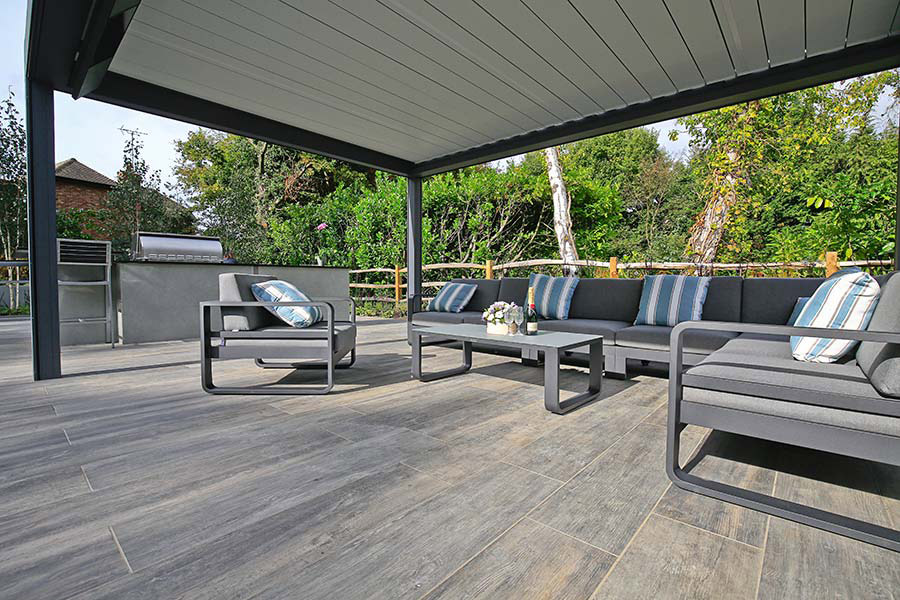 Grey Wood Effect Porcelain Tiles under a metal pergola with grey metal garden furniture.