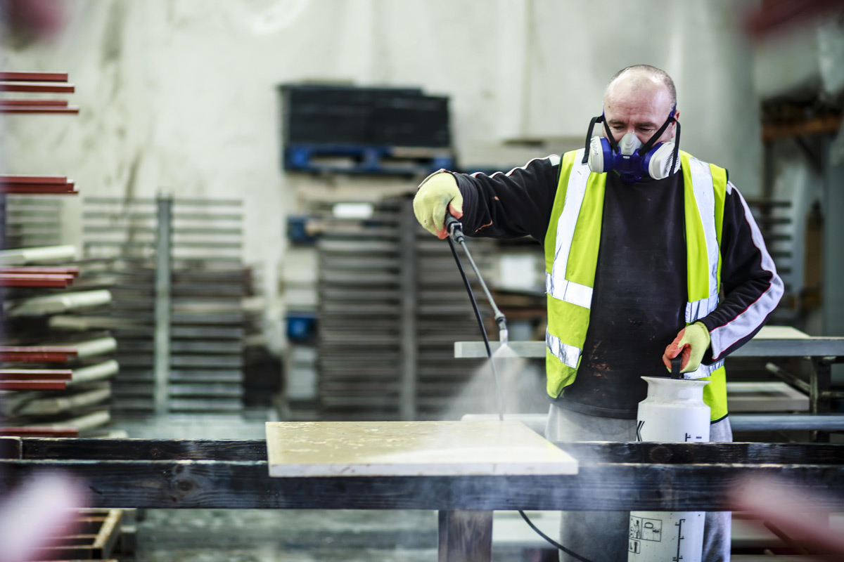 Man in protective equipment sealing natural stone in London Stone Bespoke Stone Centre