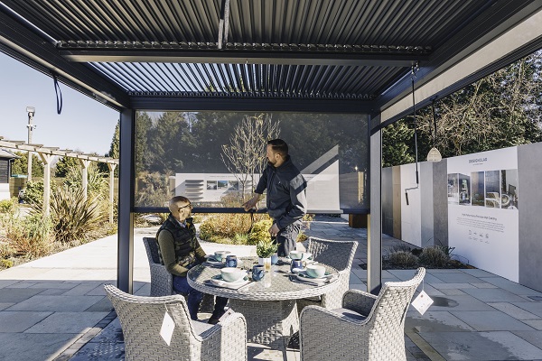 2 men under aluminium pergola with textilene side wall partially lowered.