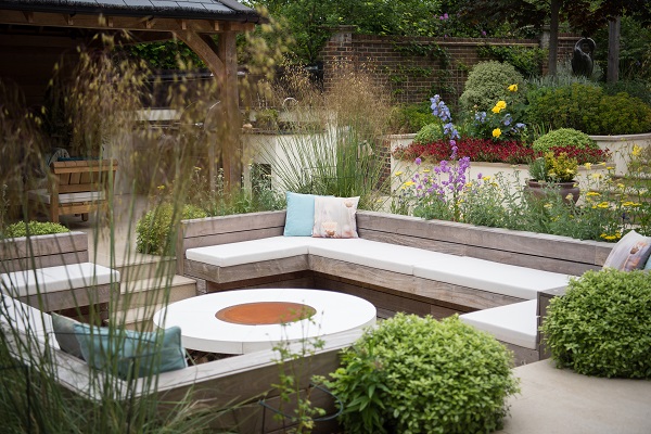 Large rectangular sunken seating area for entertaining with central round fire pit and white cushions