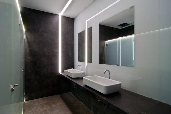 Bathroom with mirror on light wall and Vulcano Roca interior porcelain cladding tiles on washstand and adjacent wall