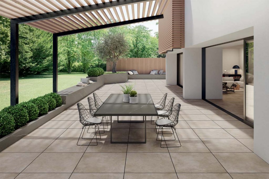 A modern design using Area 800x800 Porcelain Paving paired with a contemporary metal table and wooden pergola. 