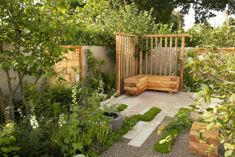 Mirage sawn sandstone planks jutting into planting and gravel, in fenced garden with L-shaped bench in corner