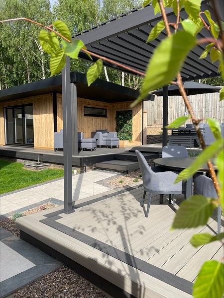 Furniture on garden room's veranda in background, seating under pergola in foreground.