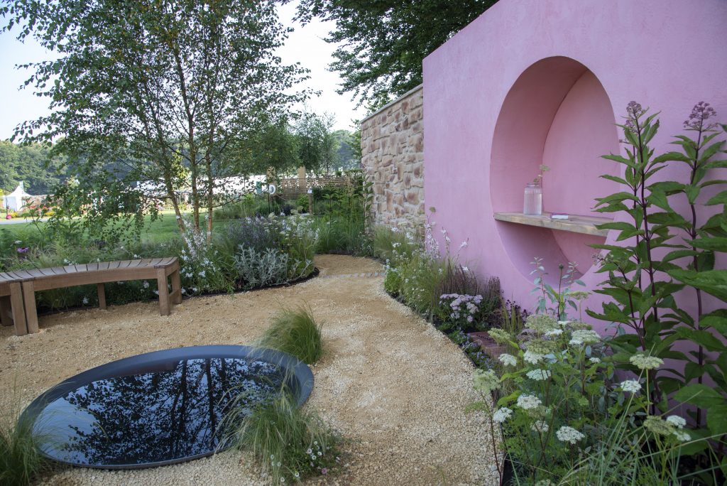 The Dreamscape Garden has interesting circular shapes to symbolize the moon. Pastel tones throughout the garden are paired with the statement pink wall. At the base of the wall our Seville Clay Pavers make an interesting addition. 