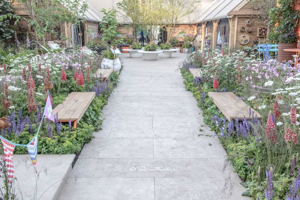 Golden Sand Porcelain Paving pathway surrounded by colourful planting at a garden show display. 