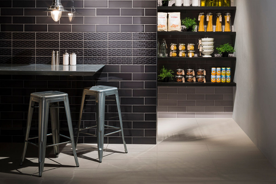 A kitchen wall with Noir gloss British made ceramic tile with band of Decor textured tiles