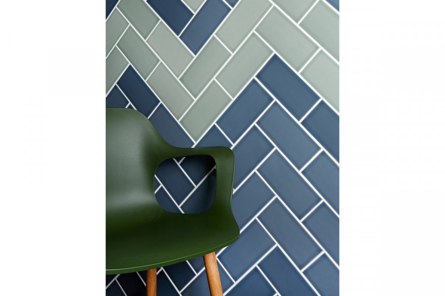 A green plastic chair against a wall of British made ceramic Savoy slate and Sage wall tiles from London Stone