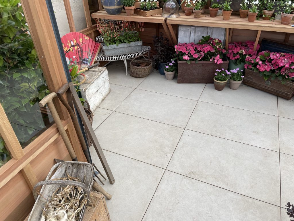 Our Florence Grey Porcelain Paving makes a beautiful backdrop for plant pots in this greenhouse.