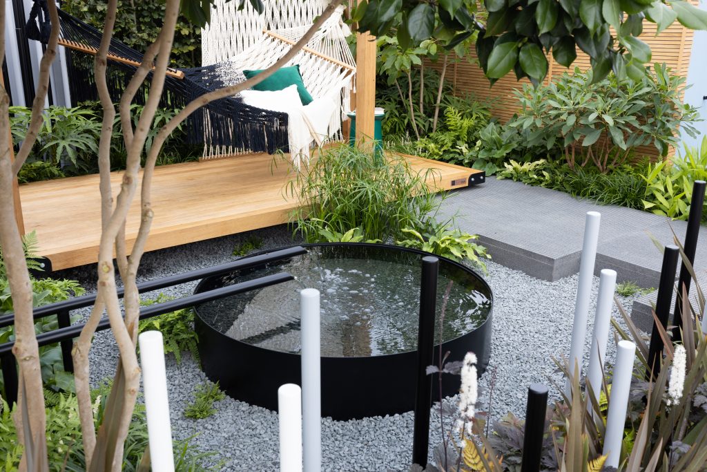 Black Granite is paired with small stone, a wooden decking, circular water feature and hammock to create the ideal spot for relaxing. 