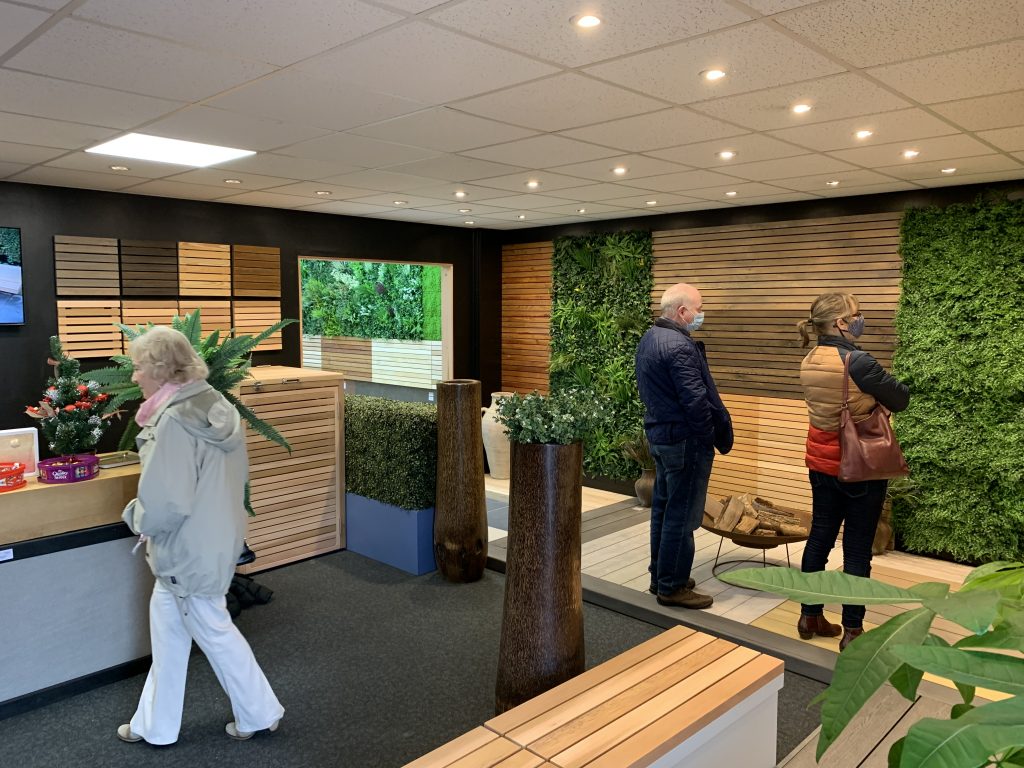 Fencing panels are fixed on the walls next to living plant walls. Decking has been laid on the floor as a walkway.