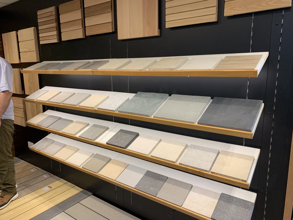 Large porcelain and natural stone samples sit on shelves in the wall.