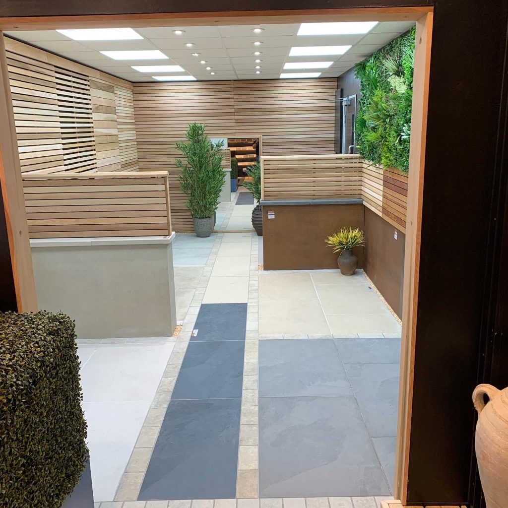 Various porcelain and natural stone paving products have been laid on the showroom floor, with fencing options on the walls. 