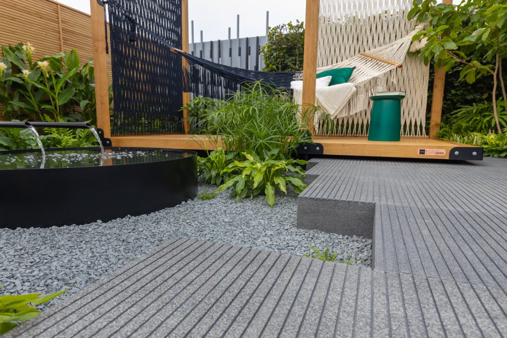 A Black Granite pathway leads to a decked area with a hammock and a water feature sits to the left. 