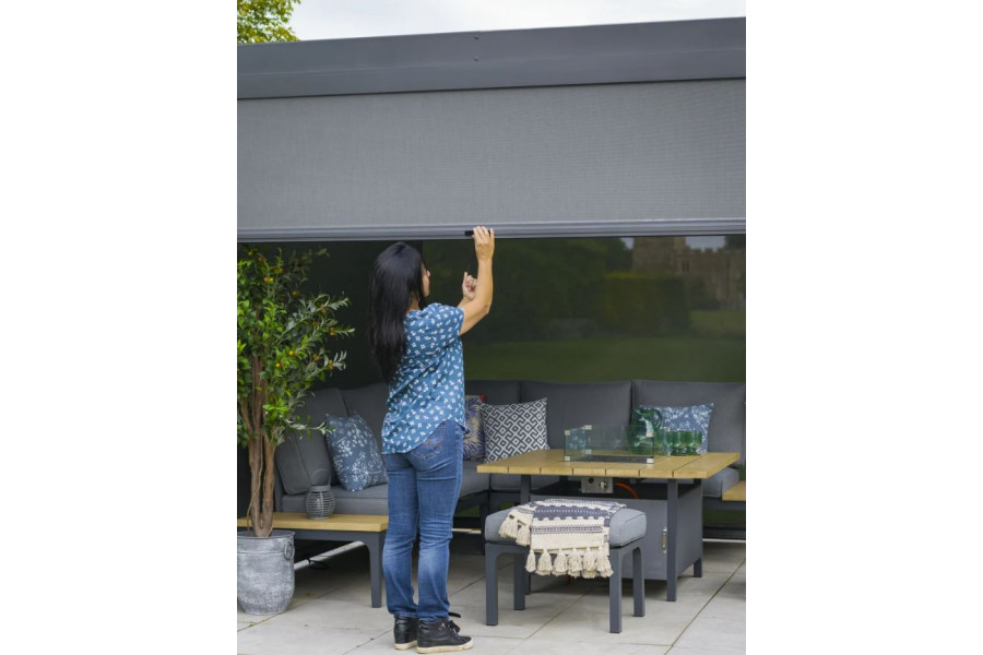 Our grey pergola site on a paved area above garden furniture, with the side wall being pulled down by hand. 