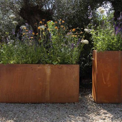 Our Corten Steel Cube Trough Planter and Corten Steel Tall Cube Planter sit side by side, filled with plants.