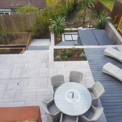 Travertine Dark Porcelain Paving and Trex Island Mist Grooved Decking are seen across a multi-levelled garden.