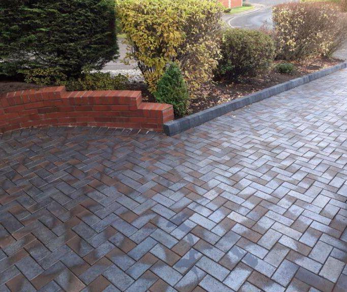 Part of Delta Blue Brown Clay Pavers driveway with wall and planted border