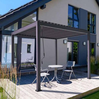 Nova Proteus dark grey metal pergola anchored on decking with bistro set beneath