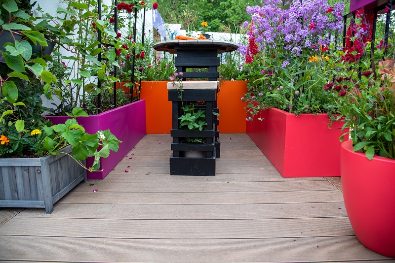 Warm Teak Composite Decking on Cirrhus Garden, with planters, RHS Chelsea 2022. Design by Jason Williams.