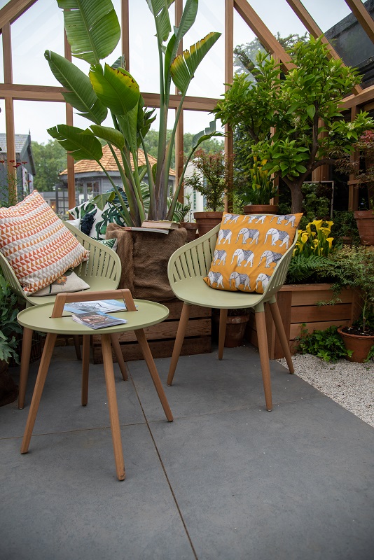 Table and chairs inside greenhouse, on Anthracite 800x800 porcelain paving. Gabriel Ash trade stand, RHS Chelsea Flower Show 2022
