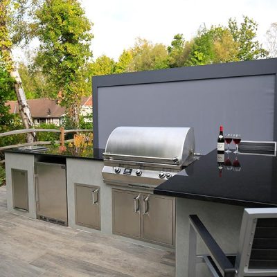 An outdoor kitchen area designed by Karen McClure featuring our Cinder Porcelain Paving.
