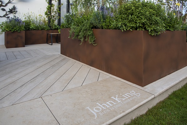 Stone patio idea of engraved Jura beige step at edge of Millboard deck. John King Brain Tumour Foundation Garden, RHS Chelsea 2022.