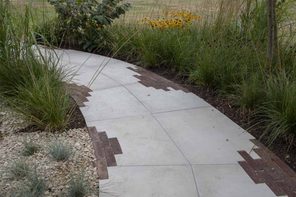 Bexhill Clay Pavers create decorative half lozenge patterns at edge of Venetian Beige Porcelain path.