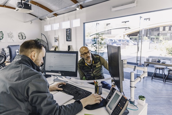 Salesman and customer face each other across desk in paving showroom, Coolings, Knockholt, Kent