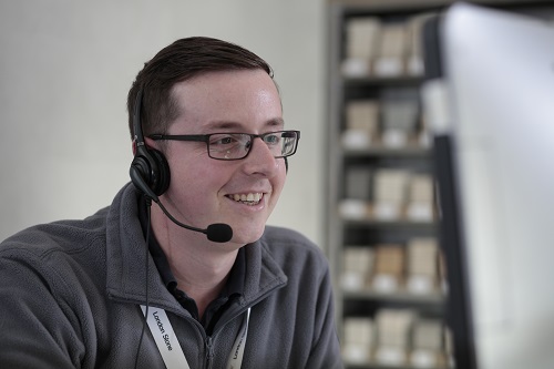 Head and shoulders of man in glasses with headset, looking off screen. 