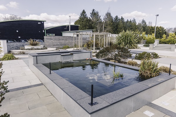 Different stone slabs surround rectangular pond with planting at London Stone outdoor paving showroom, Coolings, Knockholt, Kent