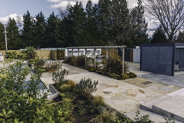 Long paved area showing different types o/f paving, with planted borders and pergola at Kent paving showroom.