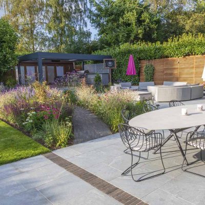 Large L-shaped area, paved with Versilia porcelain pavers,, with outdoor furniture and garden studio.