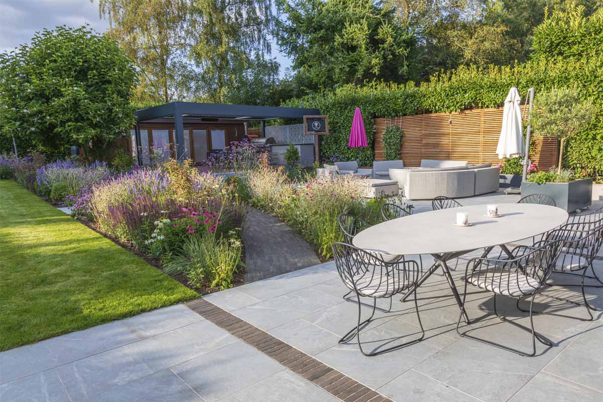 Large L-shaped area, paved with Versilia porcelain pavers,, with outdoor furniture and garden studio.