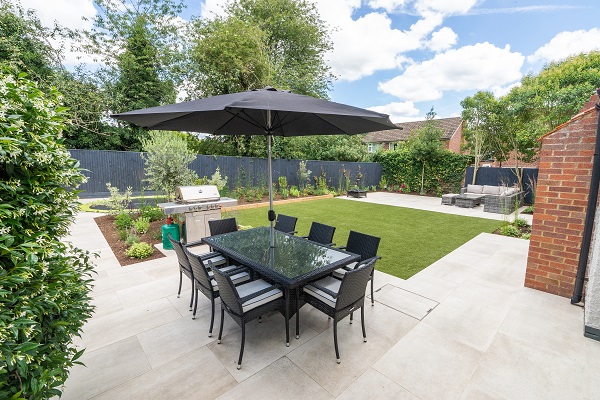 Garden dining set on Cream porcelain garden tiles with lawn beyond.