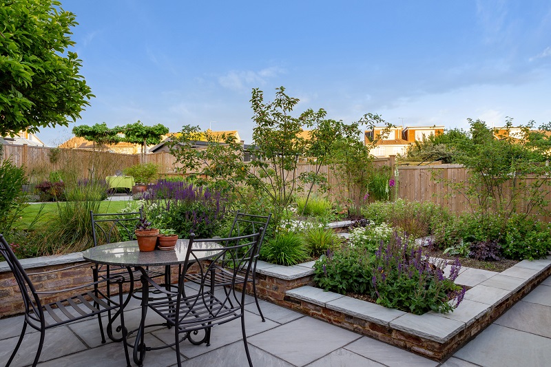 Patio set sits on Kandla Grey Indian sandstone paving next to raised beds