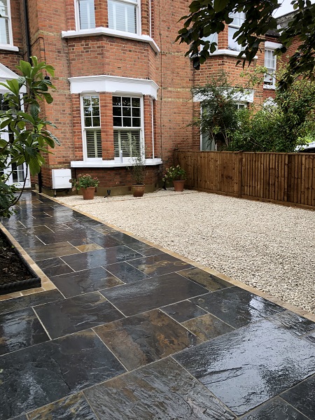 Rustic Slate pathway next to wide gravel strip leading to front of period house.